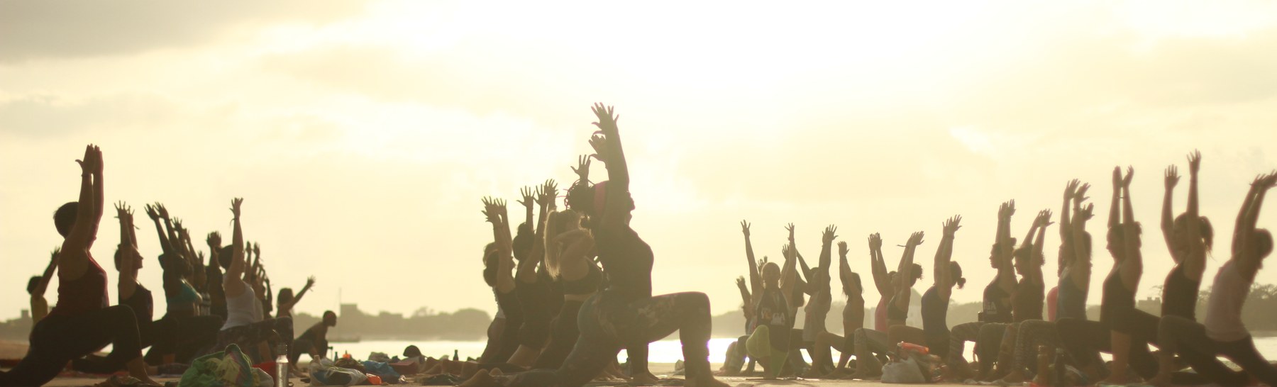 Yoga class practising together at sunset by the water